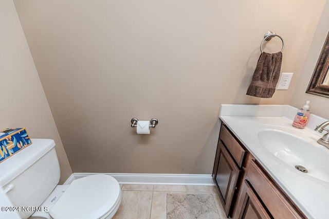 half bathroom with toilet, baseboards, and vanity