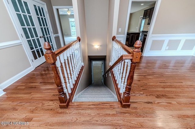 stairway with wainscoting, wood finished floors, and a decorative wall