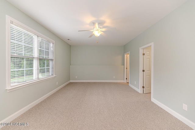 empty room featuring light carpet, a ceiling fan, and baseboards