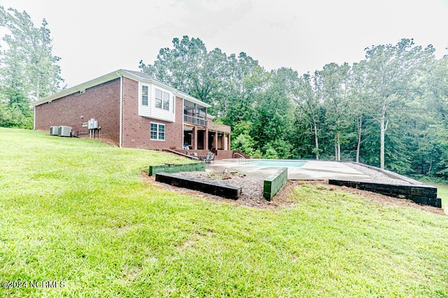 exterior space featuring cooling unit, brick siding, a patio, and a lawn