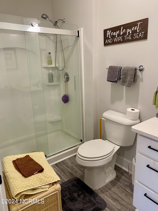 bathroom featuring hardwood / wood-style flooring, toilet, vanity, and a shower with shower door