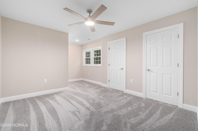 unfurnished bedroom featuring carpet floors, ceiling fan, and multiple closets