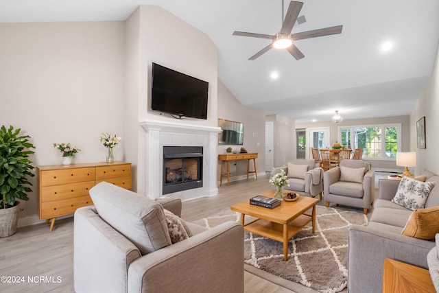 living room with light hardwood / wood-style flooring, vaulted ceiling, ceiling fan, and a premium fireplace