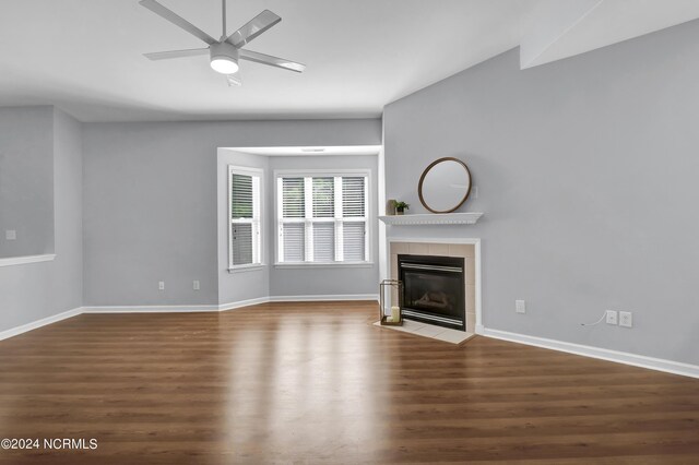 unfurnished living room featuring a tiled fireplace, wood-type flooring, and ceiling fan