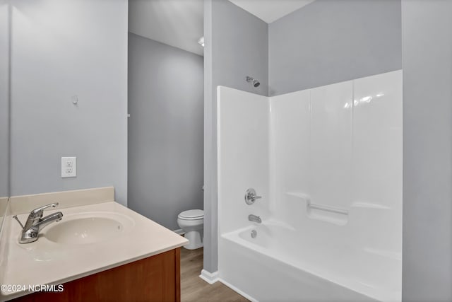 full bathroom with vanity, washtub / shower combination, toilet, and hardwood / wood-style flooring