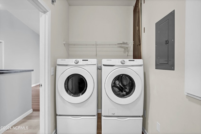 clothes washing area with washing machine and clothes dryer, hardwood / wood-style flooring, and electric panel