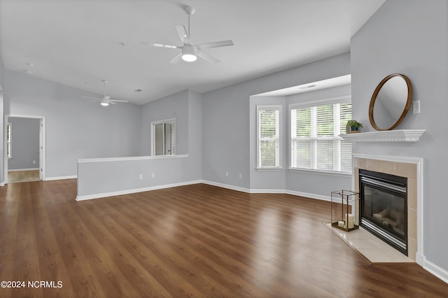 unfurnished living room featuring a tiled fireplace, wood-type flooring, and ceiling fan