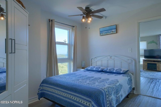 bedroom with ceiling fan, multiple windows, and light hardwood / wood-style flooring