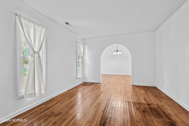 spare room featuring a notable chandelier and hardwood / wood-style flooring