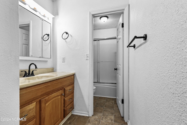 full bathroom featuring a textured ceiling, toilet, vanity, tile patterned flooring, and bath / shower combo with glass door