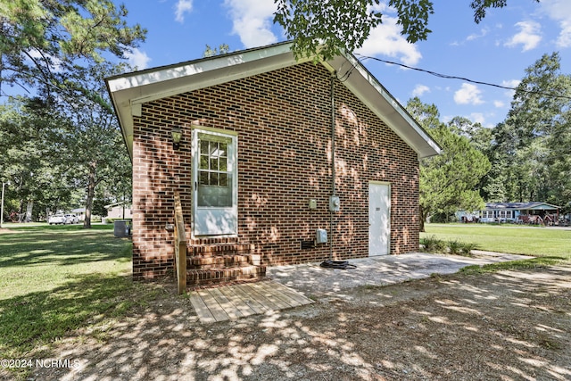 exterior space featuring a lawn, cooling unit, and a patio area