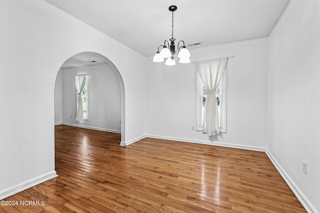 spare room featuring a notable chandelier and hardwood / wood-style flooring