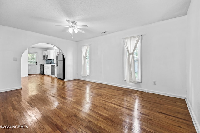 unfurnished living room featuring ceiling fan, a textured ceiling, and hardwood / wood-style flooring