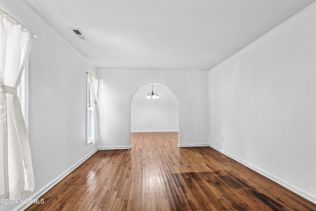 spare room featuring an inviting chandelier and hardwood / wood-style floors