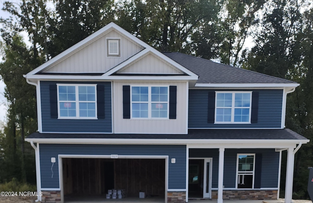 view of front of property with a porch, stone siding, board and batten siding, and a garage