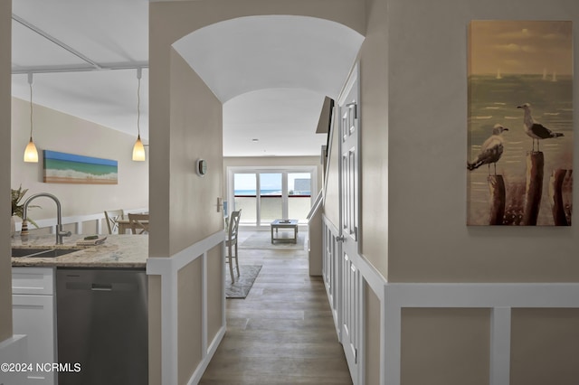 hallway featuring arched walkways, wood finished floors, and a sink