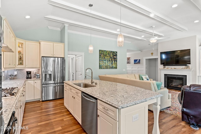 kitchen with appliances with stainless steel finishes, decorative light fixtures, sink, a breakfast bar area, and a kitchen island with sink