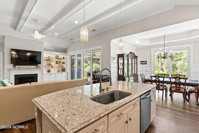 kitchen featuring decorative light fixtures, a kitchen island with sink, sink, and light stone countertops