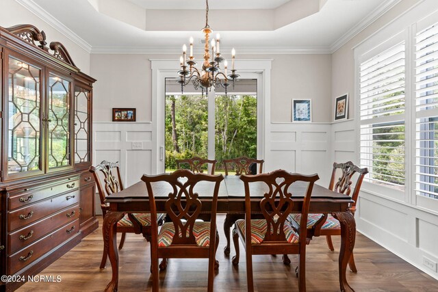 dining area featuring ornamental molding, a chandelier, hardwood / wood-style floors, and a tray ceiling