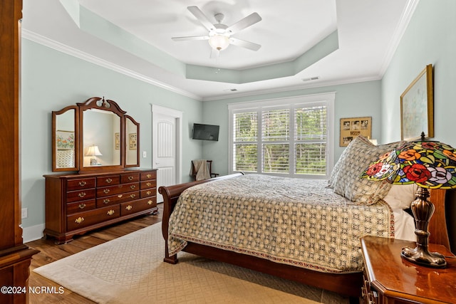 bedroom featuring crown molding, ceiling fan, a tray ceiling, and dark hardwood / wood-style flooring