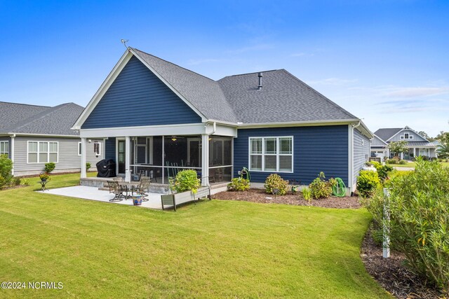 back of property featuring a sunroom, a patio area, and a lawn