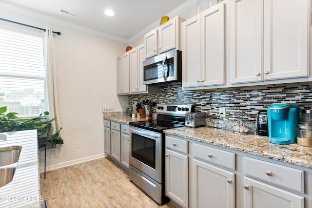 kitchen with white cabinetry, tasteful backsplash, appliances with stainless steel finishes, and ornamental molding