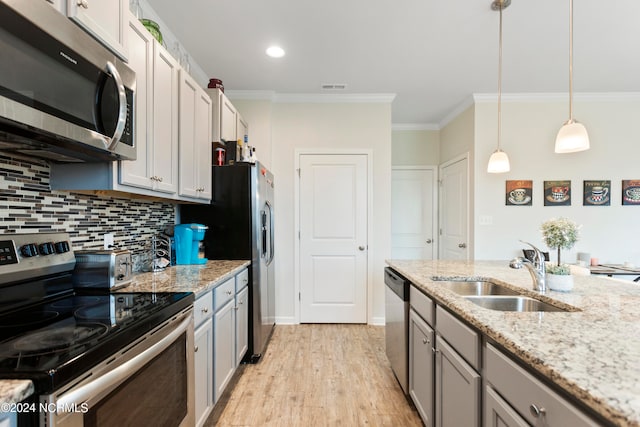 kitchen with stainless steel appliances, light hardwood / wood-style floors, hanging light fixtures, sink, and ornamental molding