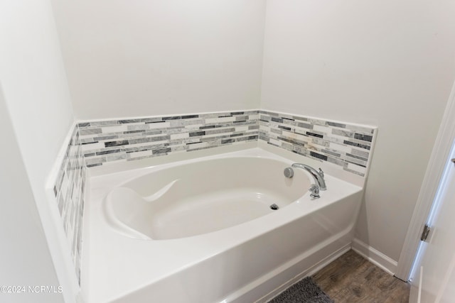 bathroom with hardwood / wood-style floors and a bath