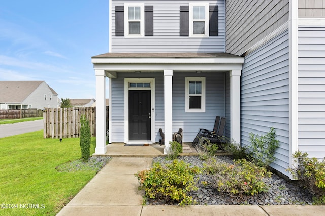 doorway to property featuring a lawn and covered porch