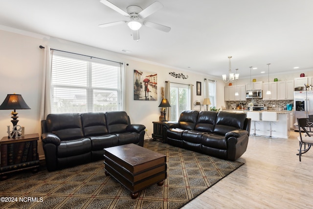 living room with hardwood / wood-style floors, ceiling fan with notable chandelier, and crown molding