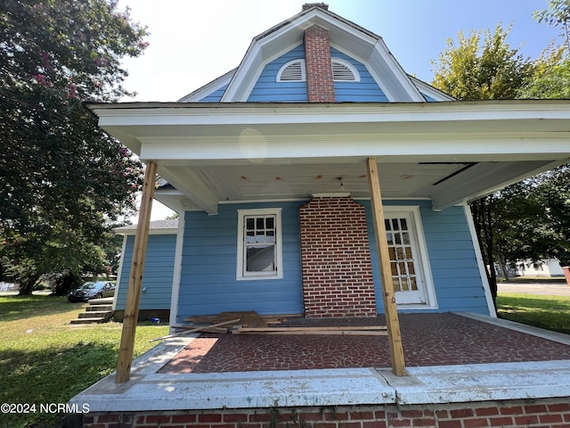 view of exterior entry featuring a porch and a gambrel roof