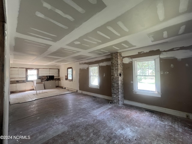 unfurnished living room with a wealth of natural light, baseboards, and ornate columns