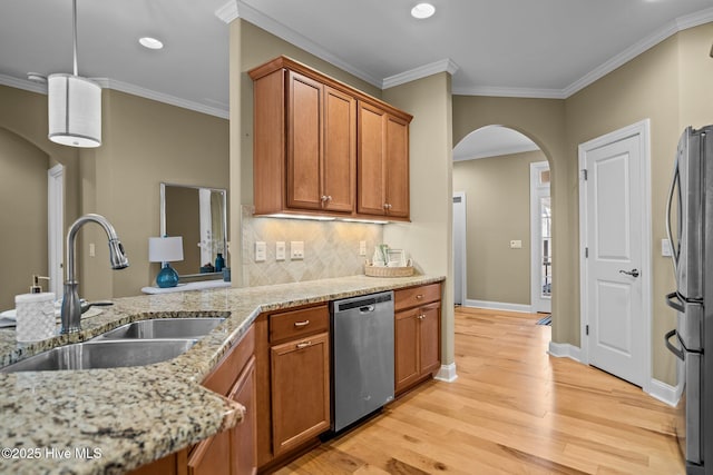 kitchen with sink, light wood-type flooring, appliances with stainless steel finishes, light stone countertops, and crown molding