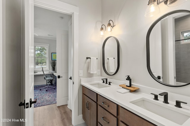 full bathroom with crown molding, double vanity, a sink, and wood finished floors