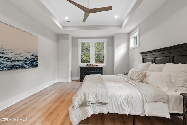 bedroom featuring recessed lighting, wood finished floors, visible vents, baseboards, and a tray ceiling