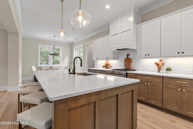 kitchen with crown molding, a breakfast bar area, decorative backsplash, stainless steel gas stove, and a sink