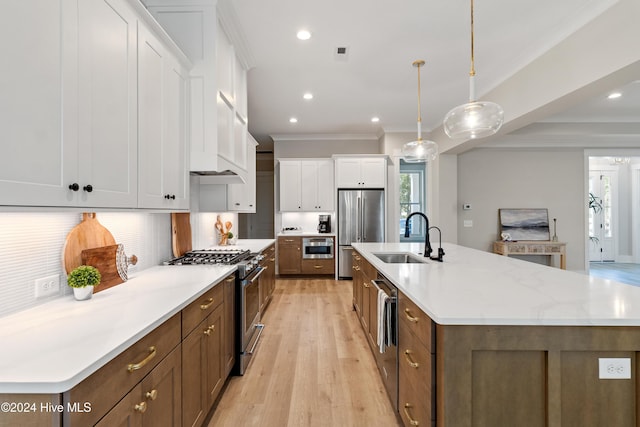 kitchen featuring a spacious island, a sink, white cabinetry, appliances with stainless steel finishes, and crown molding