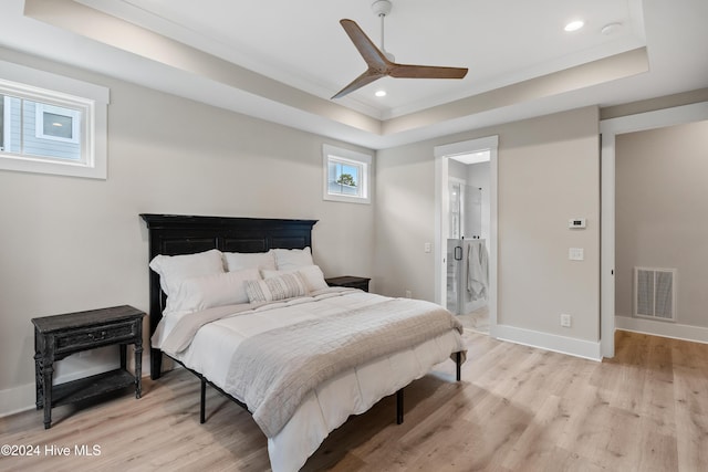 bedroom featuring light wood-style flooring, a raised ceiling, and visible vents