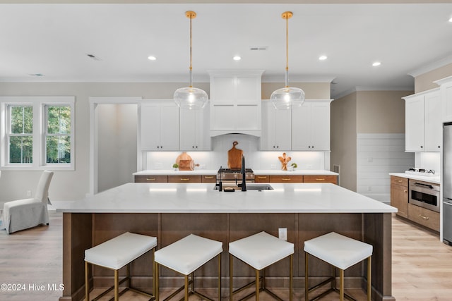 kitchen featuring oven, premium range hood, a sink, and light wood-style flooring