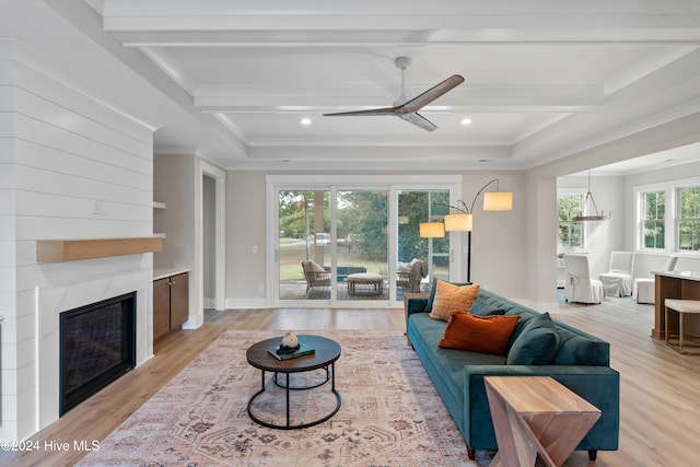 living room featuring coffered ceiling, light wood-style flooring, beamed ceiling, crown molding, and a fireplace