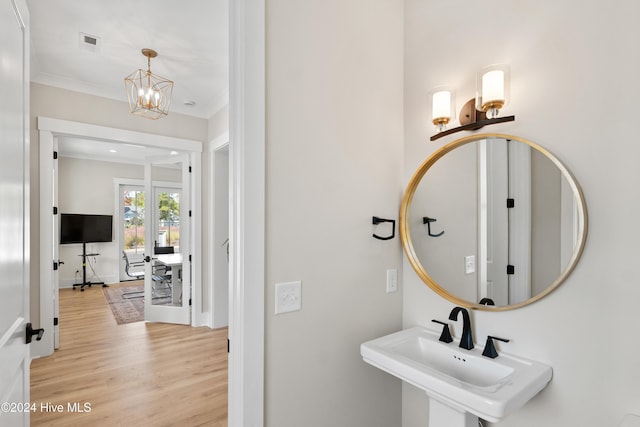 bathroom featuring visible vents, wood finished floors, crown molding, a chandelier, and a sink