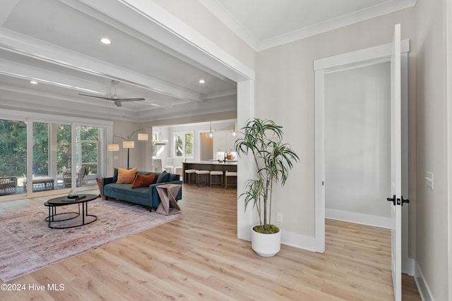 living room featuring beam ceiling, crown molding, baseboards, and wood finished floors