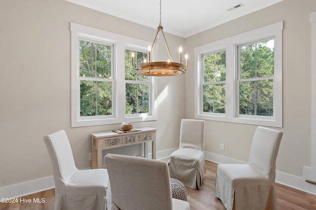 dining space featuring a notable chandelier, wood finished floors, visible vents, baseboards, and crown molding