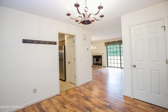 hallway with visible vents, a notable chandelier, light wood-style flooring, and baseboards