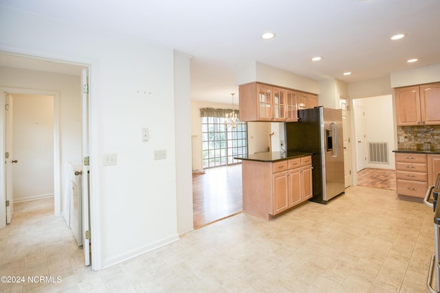 kitchen featuring stainless steel refrigerator with ice dispenser, dark countertops, visible vents, backsplash, and glass insert cabinets