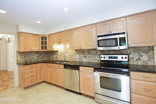 kitchen featuring appliances with stainless steel finishes, glass insert cabinets, a sink, and light brown cabinetry