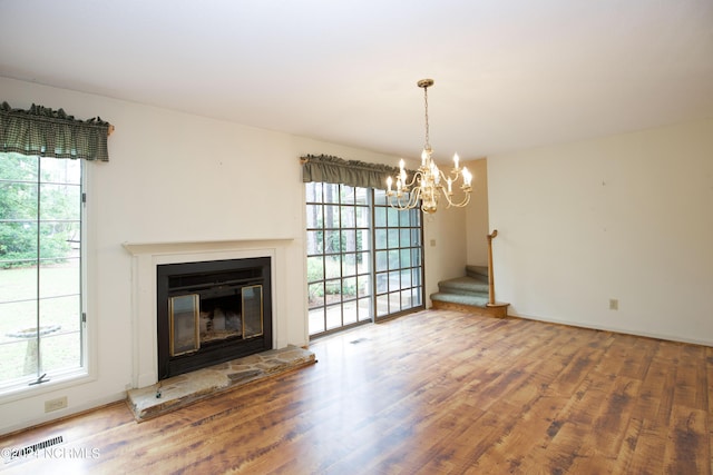 unfurnished living room featuring a glass covered fireplace, a healthy amount of sunlight, visible vents, and wood finished floors