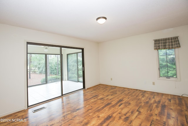 unfurnished room with wood finished floors, visible vents, and baseboards