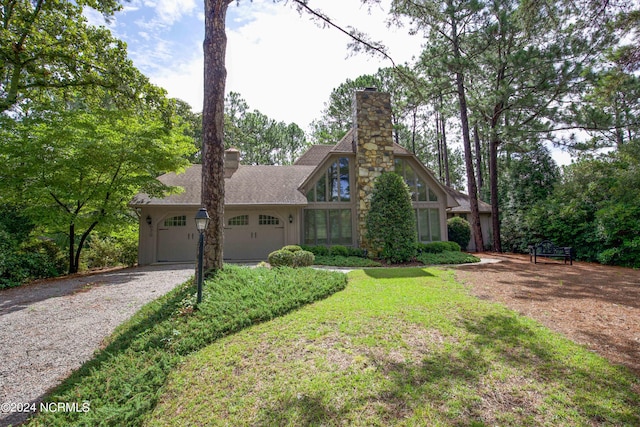 view of front of house with a garage, a front lawn, a chimney, and gravel driveway