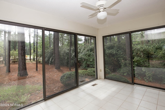 unfurnished sunroom with a ceiling fan, visible vents, and a wealth of natural light